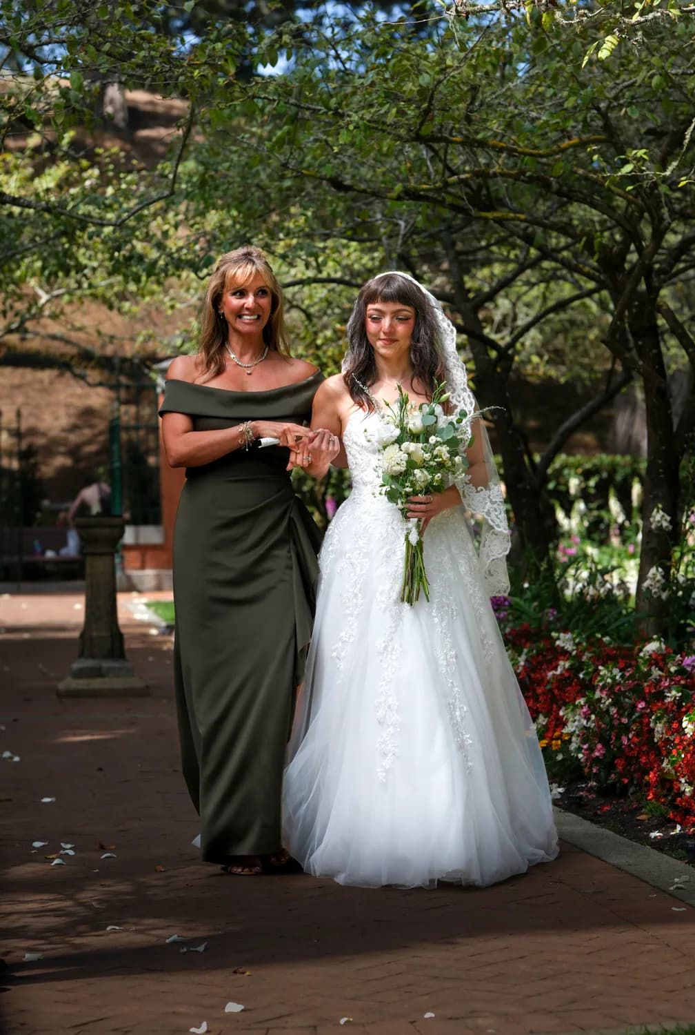 Bride walking with her mother along a garden path before the ceremony