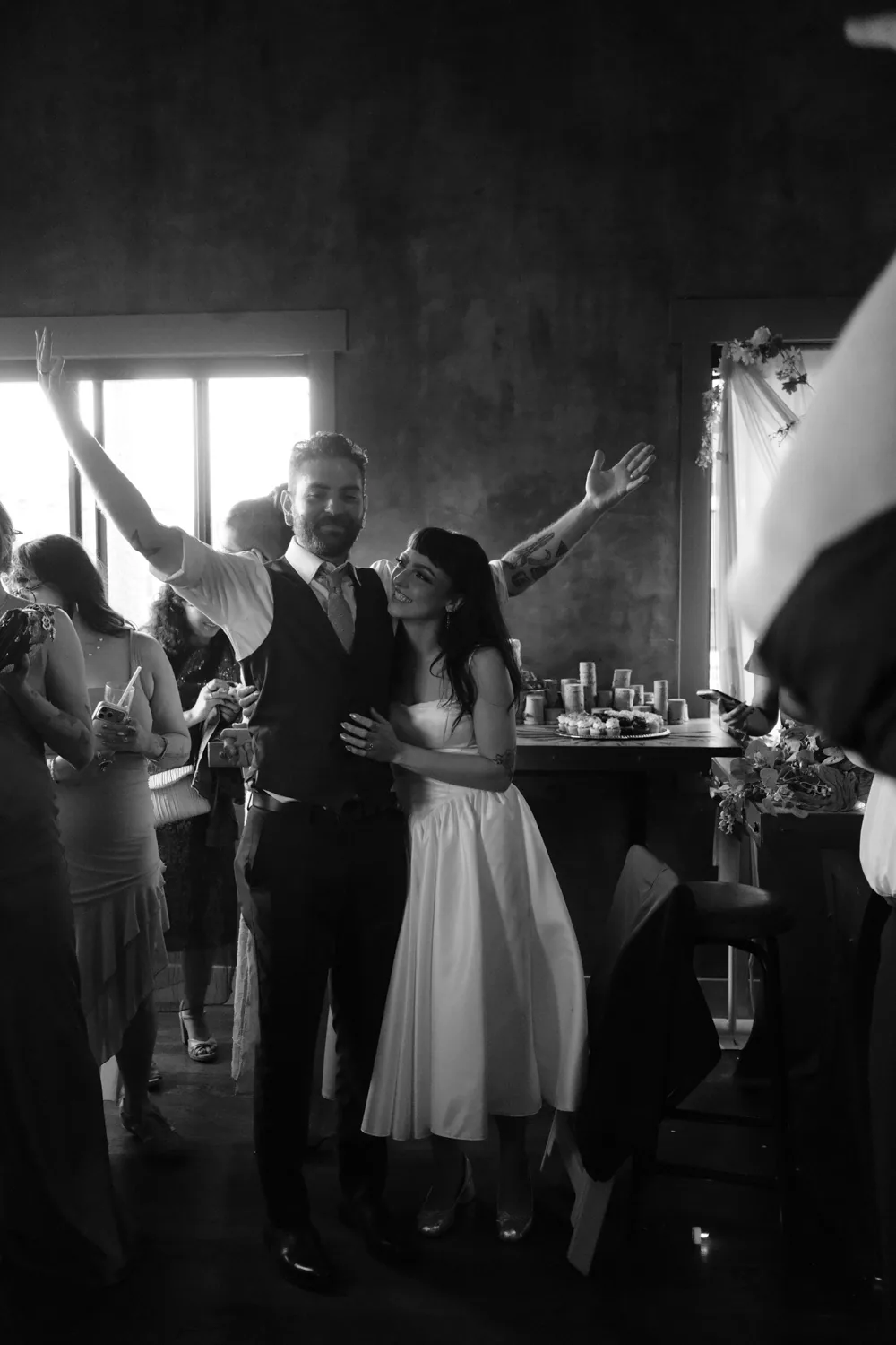 Bride and groom celebrating with raised arms at their reception, black and white