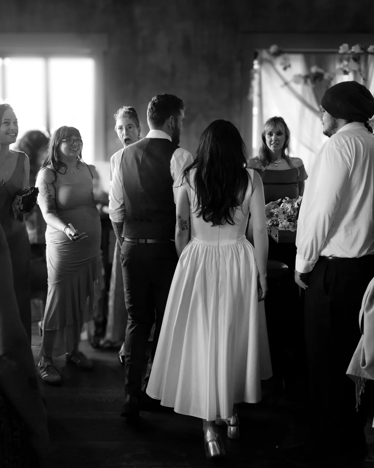 Bride and groom greeting guests at an intimate reception, black and white