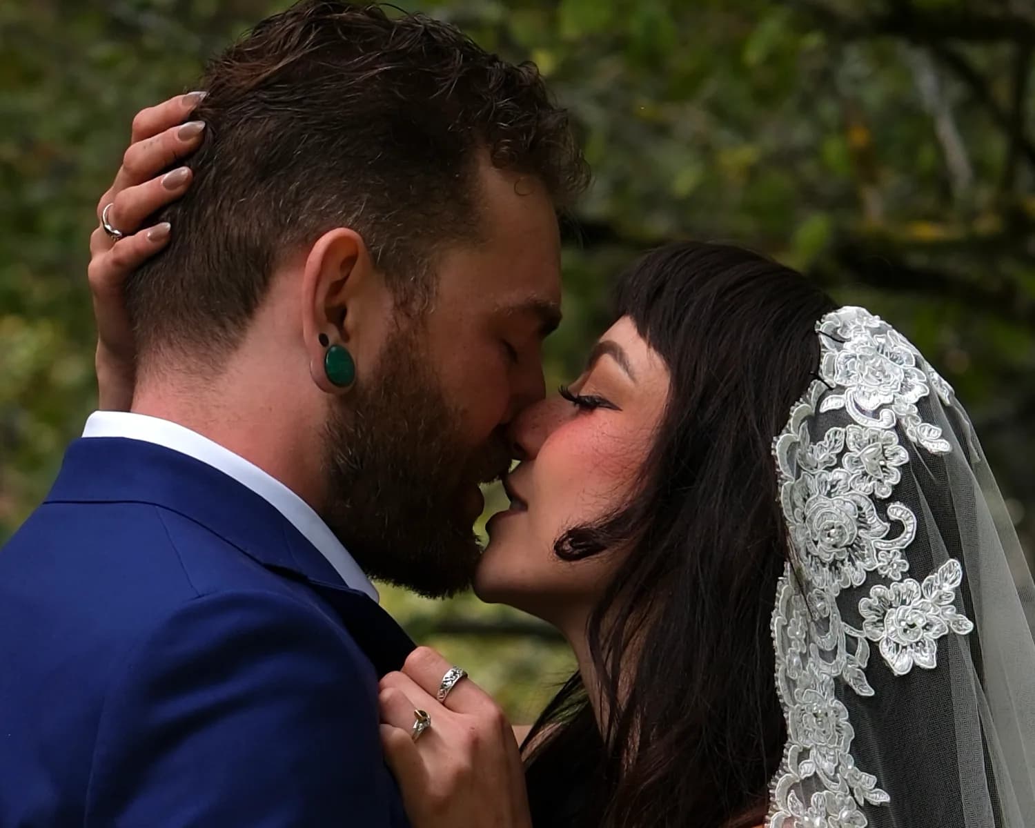 Close portrait of a couple kissing on their wedding day with a lace veil