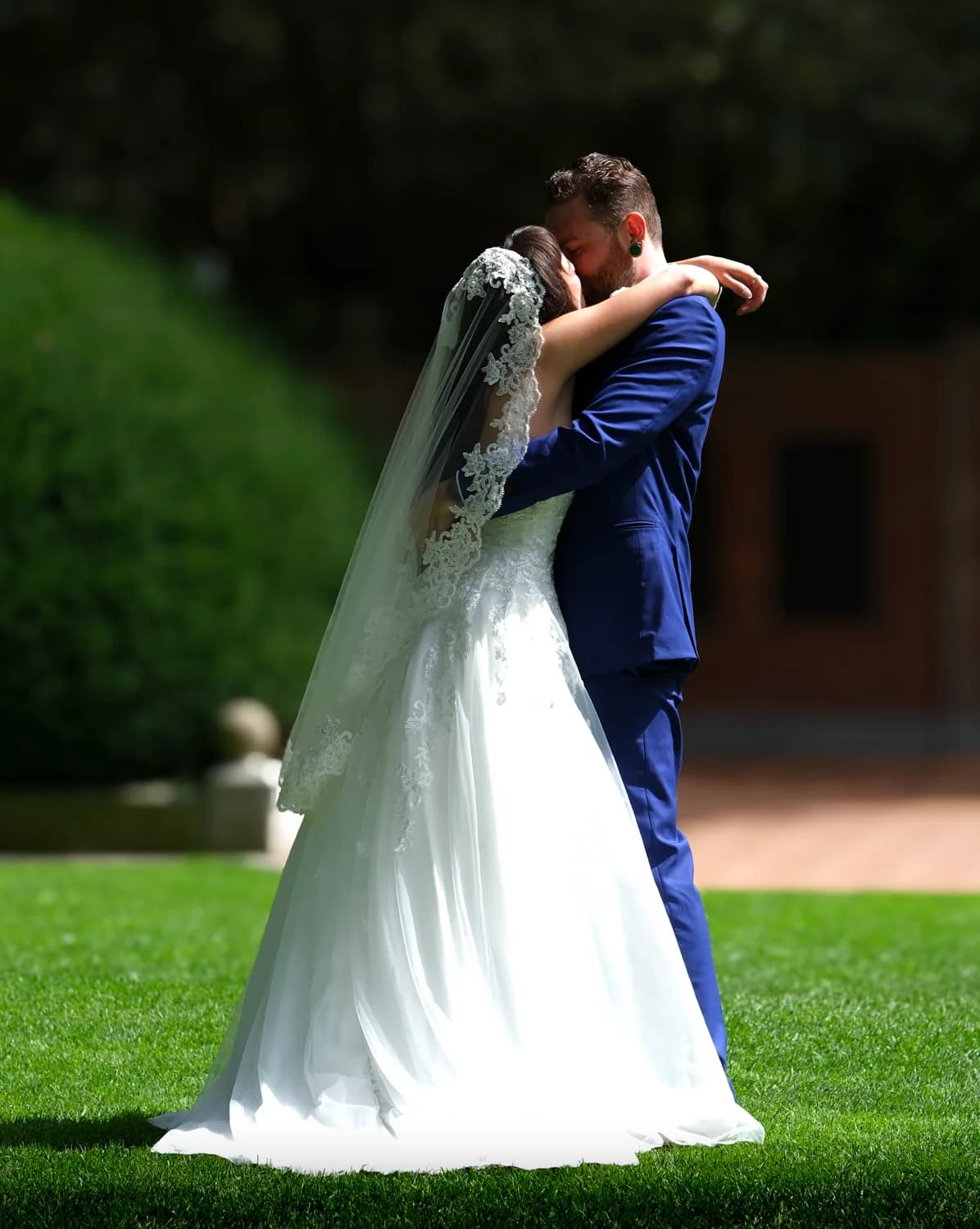 Bride and groom in an embrace on a green lawn on their wedding day