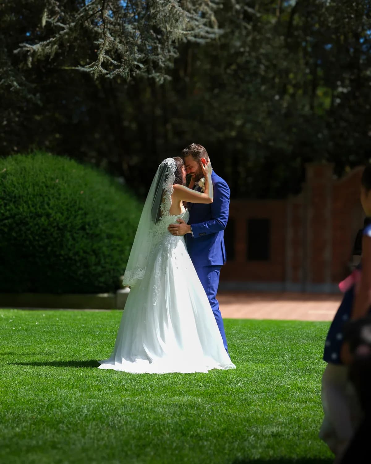 Couple holding each other close on a sunlit lawn during their intimate wedding
