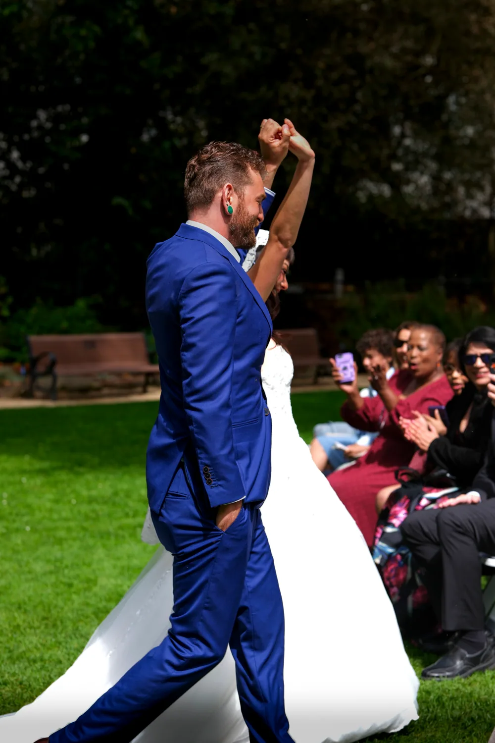 Groom raising his fist in celebration as guests cheer during the ceremony recessional
