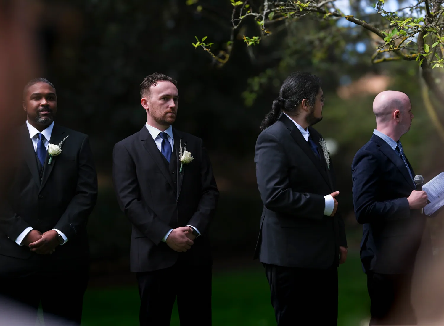 Groomsmen standing together during an outdoor garden ceremony