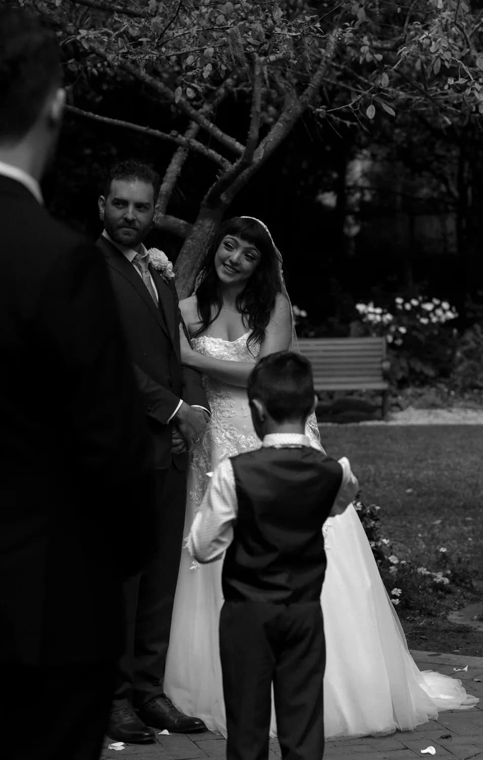 Ring bearer watching the bride and groom during an outdoor ceremony, black and white