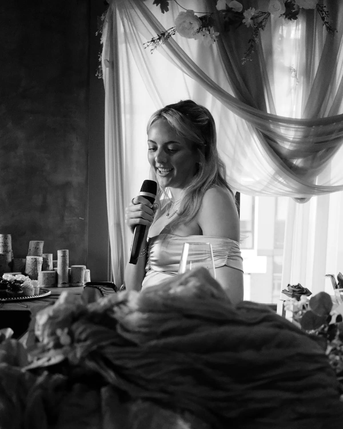 Guest giving a toast with a microphone at an intimate wedding reception, black and white