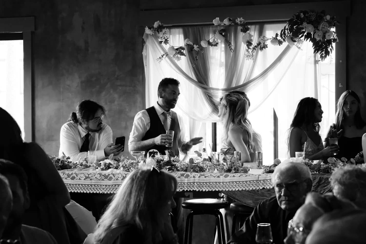 Wedding guests giving toasts at a rustic reception, black and white