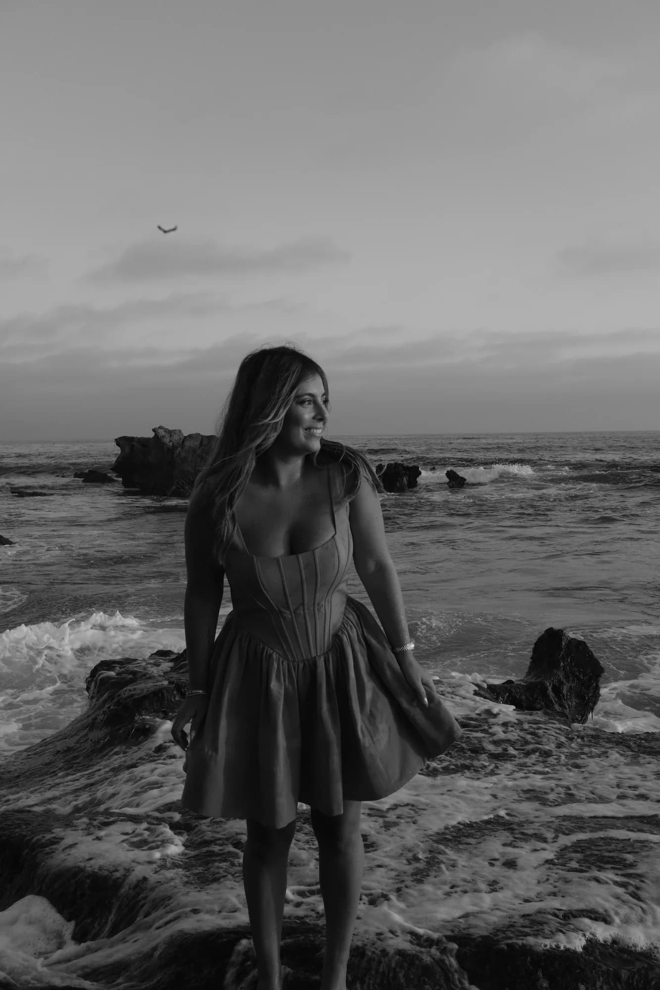 Black and white portrait of a young woman standing in the surf looking over her shoulder
