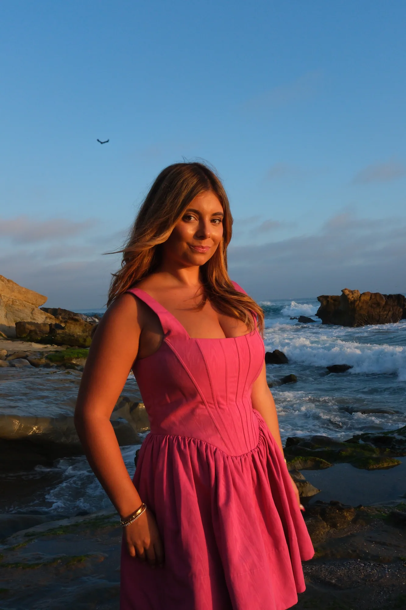Portrait of a young woman in a pink dress on the Southern California coast at golden hour