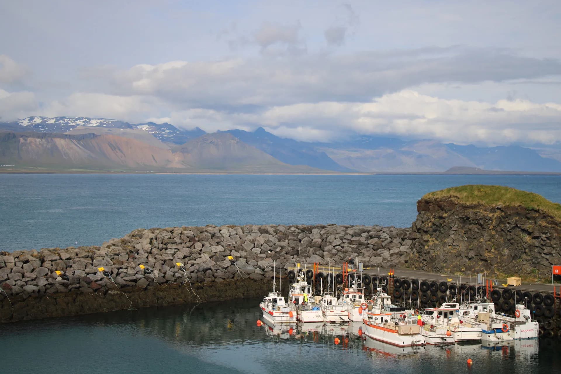Small fishing boats in a harbor with mountains across the water in Iceland