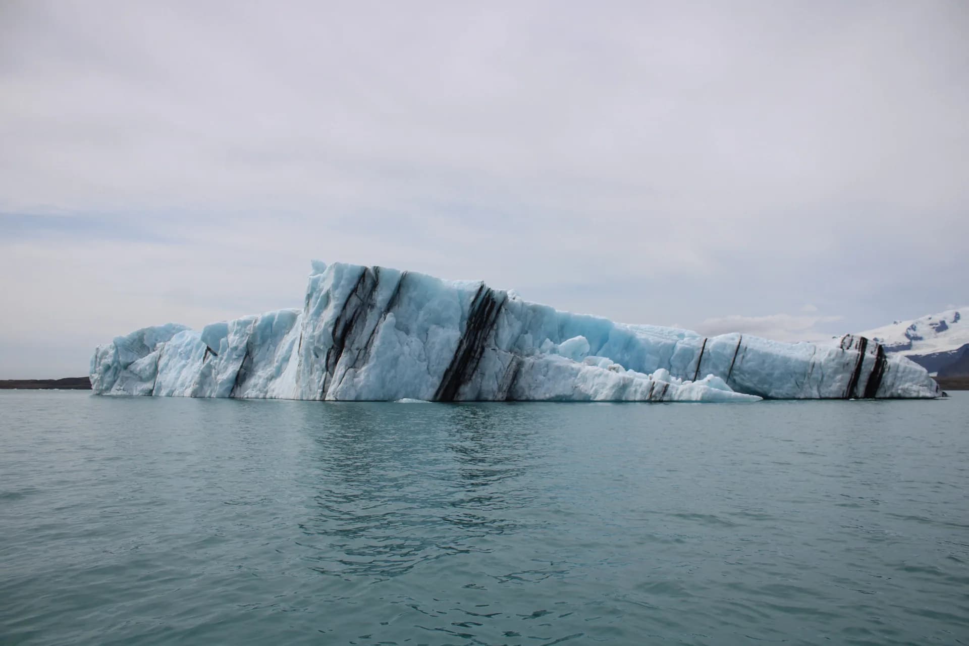 Iceberg with dark volcanic ash stripes floating on a glacier lagoon in Iceland