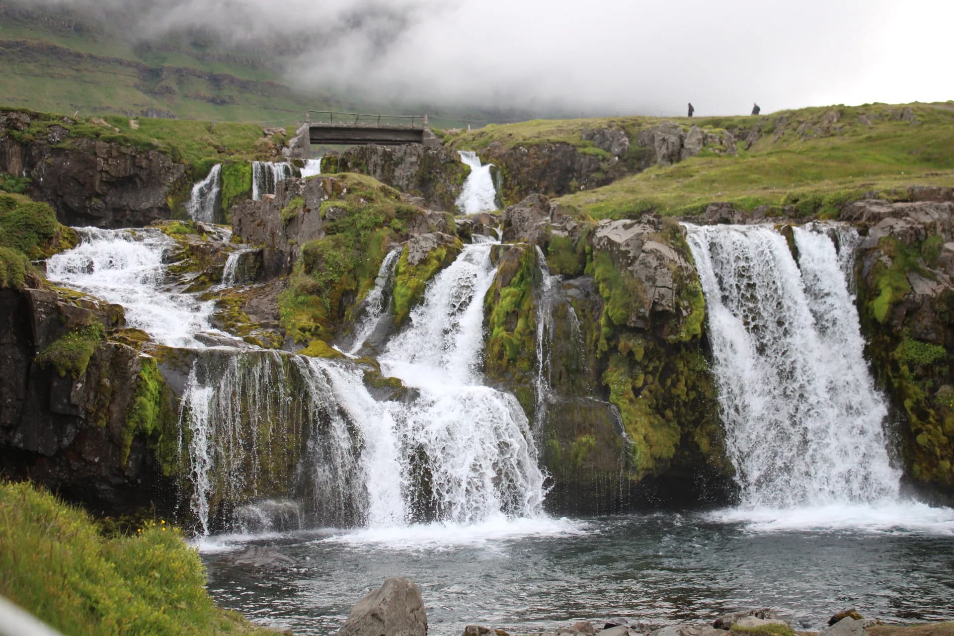 Cascading waterfalls over mossy green cliffs in Iceland