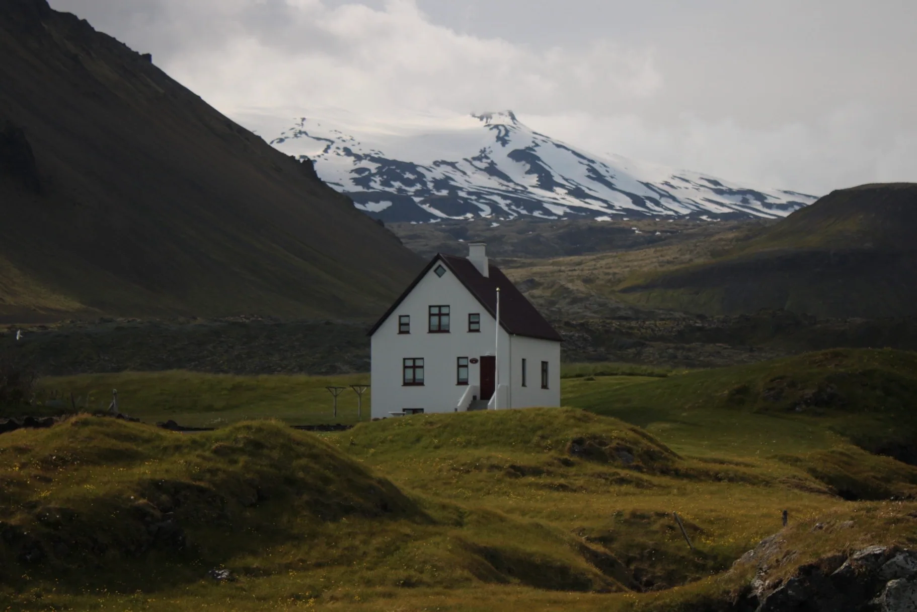 White farmhouse in front of a snow-capped mountain in Iceland