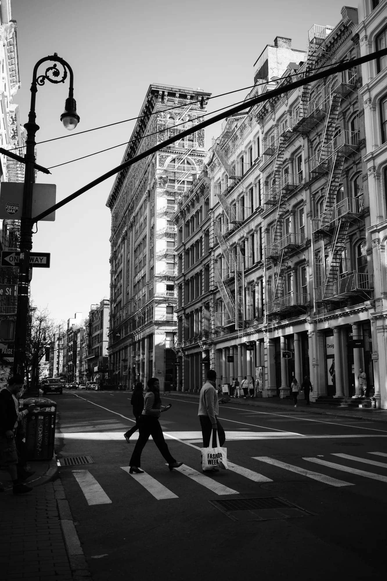 Black and white street photo of pedestrians crossing a SoHo street in New York City