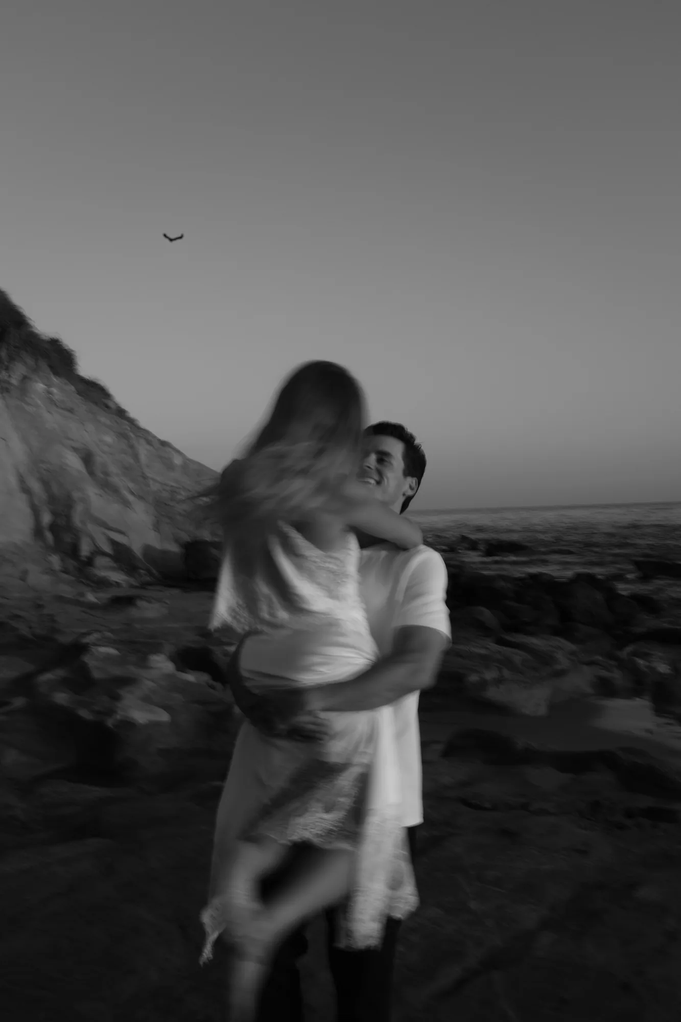 Couple twirling together during a beach engagement session, black and white